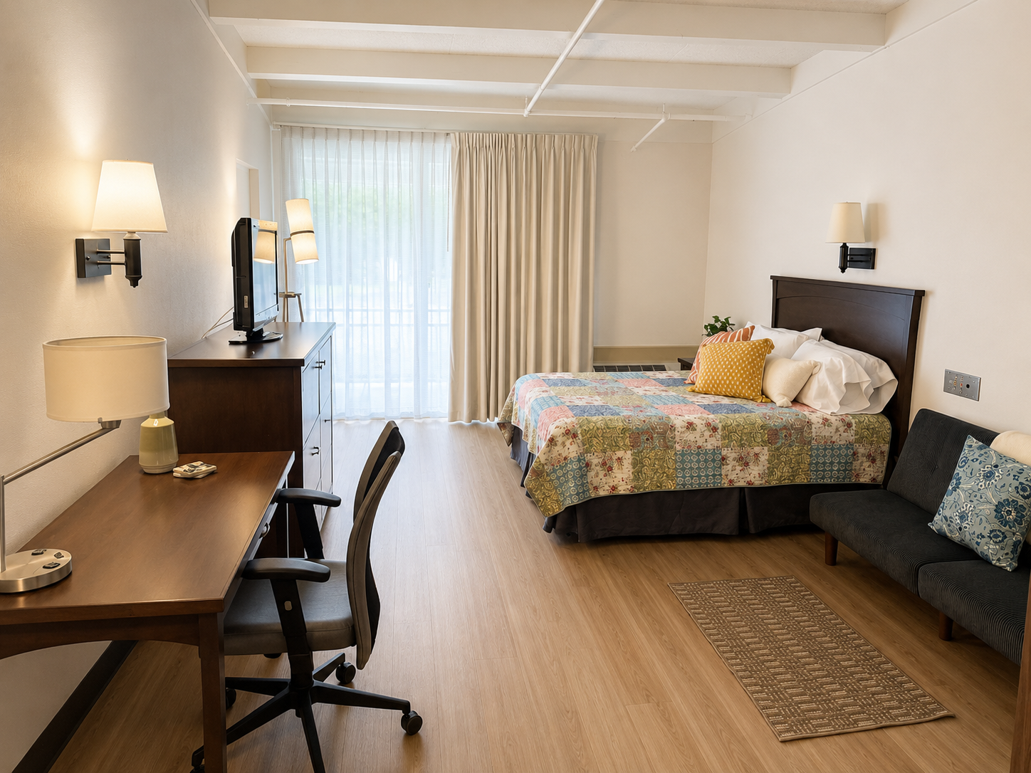 Full room view showing desk, queen bed, and seating area at The Residences, Hadley, MA