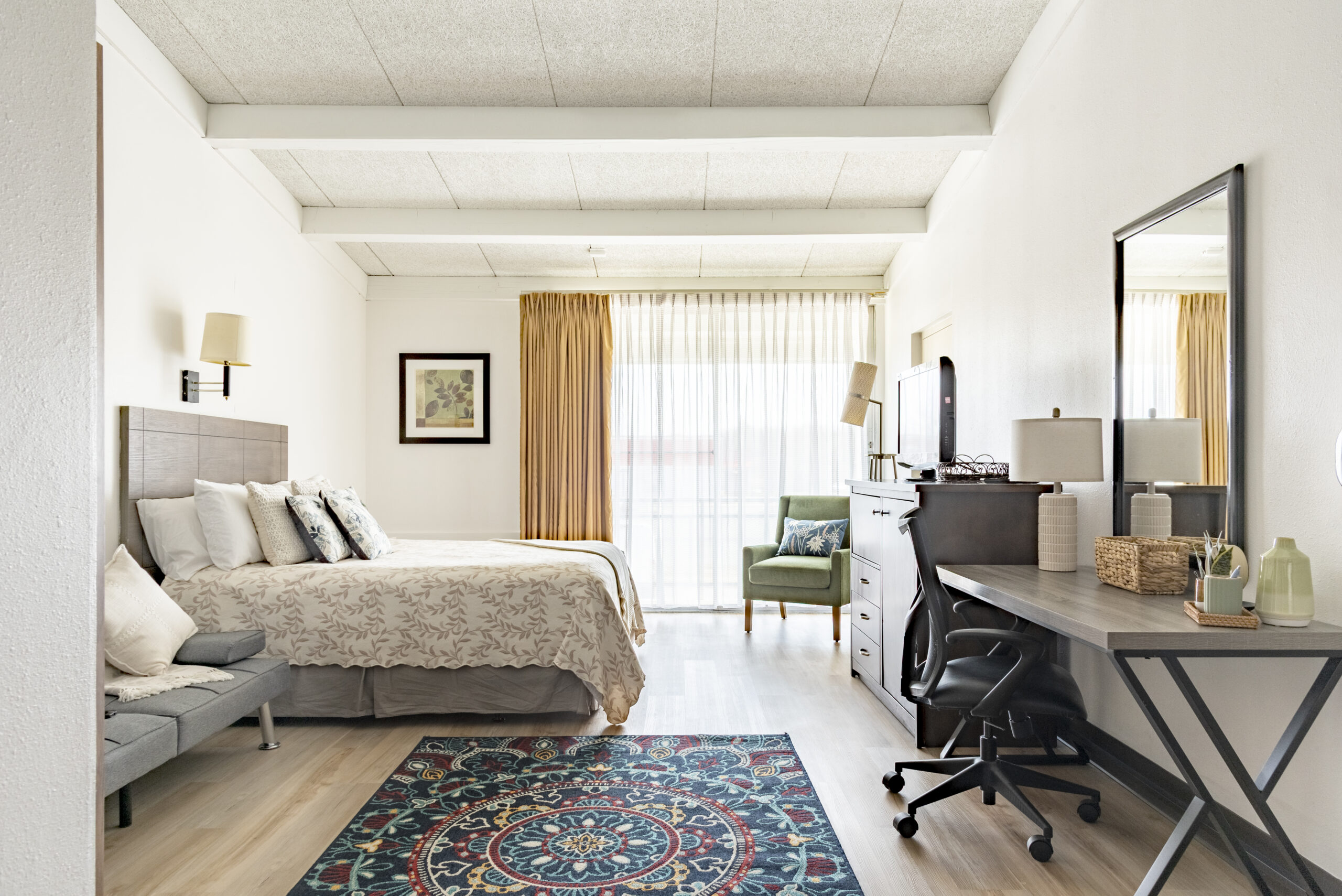 Queen bed and dedicated desk workspace in a furnished room at The Residences, Hadley, MA