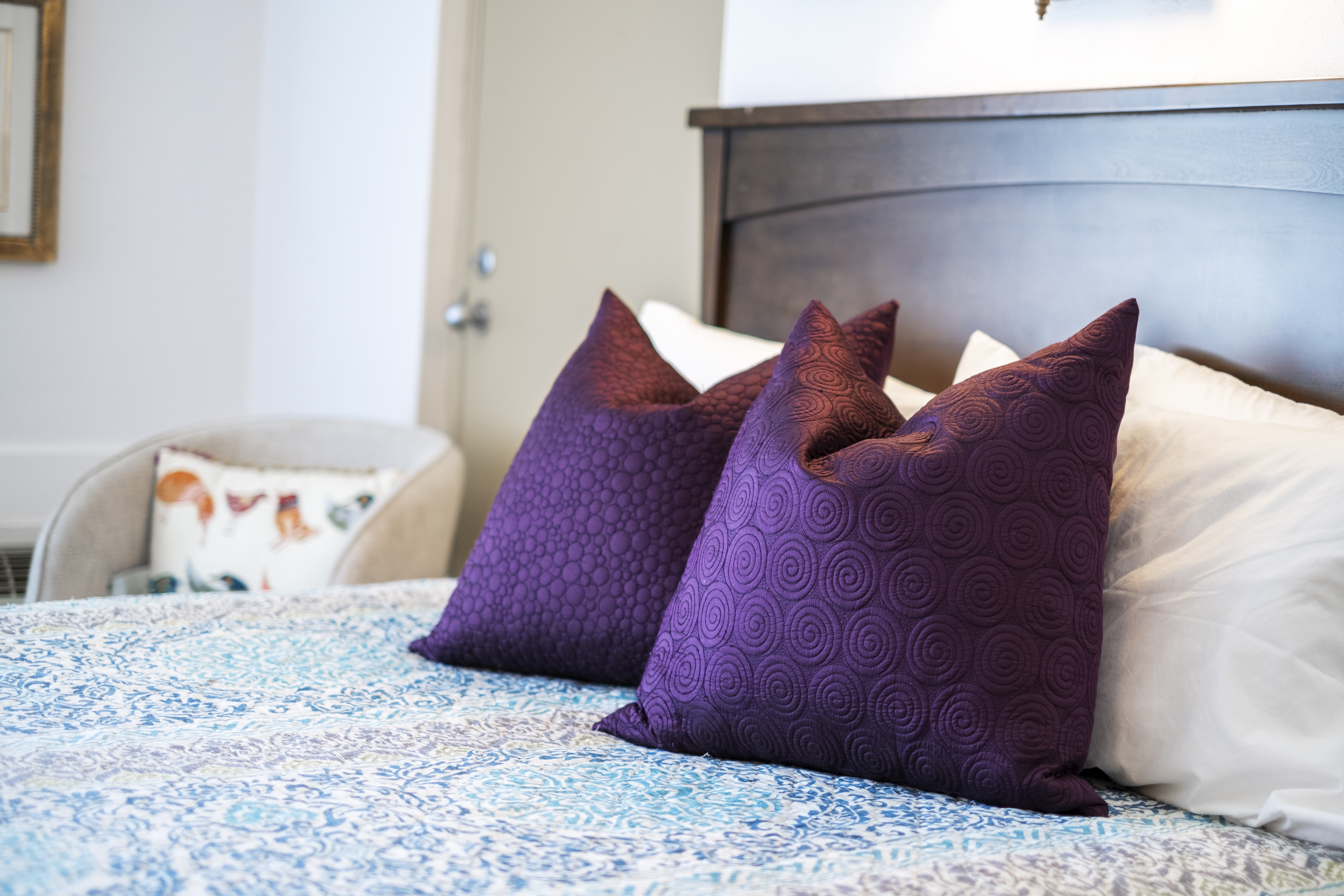 Upholstered headboard with purple pillows in furnished room at The Residences, Hadley, MA
