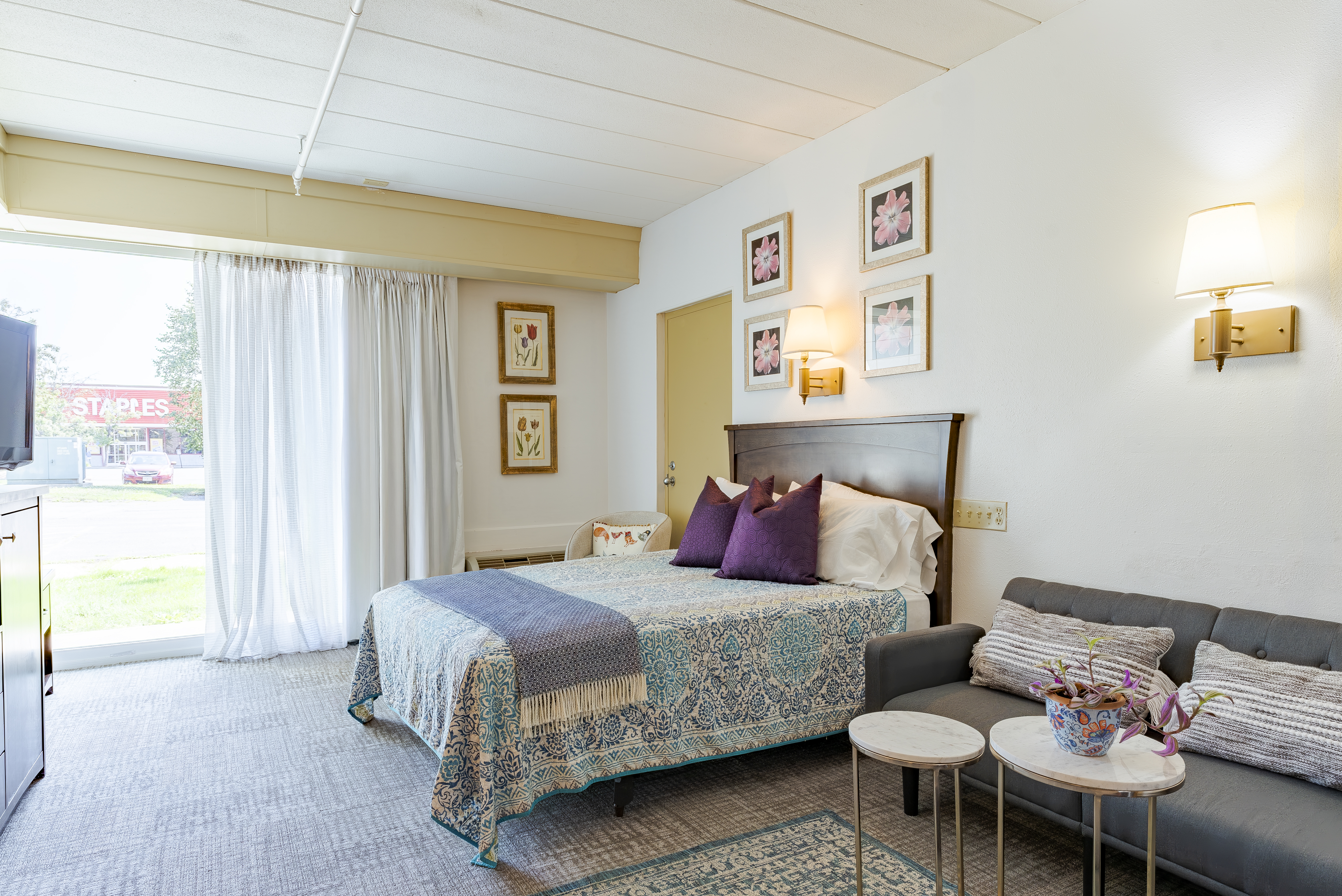 Queen bed, sofa, and patio door in furnished room at The Residences, Hadley, MA
